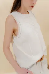 Chaleco tejido color mostaza con bordado artesanal en forma de V al tono. Tiene cuello redondo y sisas con sobretono.