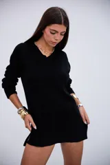 Sweater de punto acanalado color negro, con cuello en V y mangas largas. Presenta un diseño de corte holgado con aberturas laterales en el ruedo.