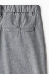 Pantalón de vestir gris claro, de corte slim fit, con bolsillos laterales y traseros. Se ajusta a la cintura con cierre y botón.