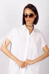 Camisa sin mangas color verde esmeralda, con cuello clásico, cierre frontal con botones y tiras regulables en los hombros.