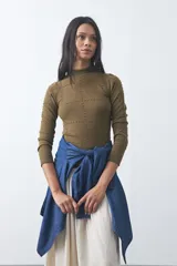 Polera de tejido de punto color celeste, con cuello alto y textura de pequeños puntos en relieve formando una cuadrícula en el frente y las mangas. De corte ajustado y manga larga.