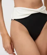 Bombacha de bikini tipo hot pant confeccionada en microfibra, con diseño bicolor en negro y blanco estilo color block. Presenta cintura alta con pretina cruzada.