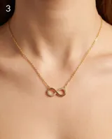 Collar de acero con baño de oro, con dije en forma de símbolo de infinito parcialmente incrustado con circonias.