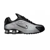 Championes Nike Shox R4 con diseño técnico, caracterizados por su sistema de amortiguación de columnas en el talón. Presentan una combinación de colores negro y plateado, con el logo de la marca en el lateral y una estructura aerodinámica.
