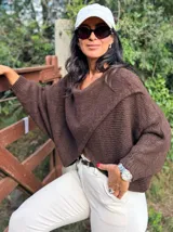 Sweater de punto gris con diseño cruzado en el frente, mangas largas con puños ajustados y corte holgado.