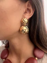 Par de aros dorados con diseño de doble esfera texturizada.