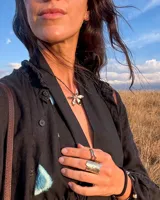 Collar tipo gargantilla con dije de flor metálica de acabado brillante, suspendido de un cordón doble de seda natural teñido a mano en color rojo.