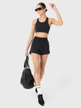 Top deportivo negro con diseño de espalda estilo racerback, confeccionado en tela suave y elástica. Cuenta con almohadillas removibles y un ajuste ceñido al cuerpo, ideal para actividades de entrenamiento.