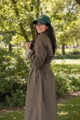 Trench coat reversible de corte clásico, color marrón con forro interior estampado a cuadros. Presenta cuello solapa, cierre frontal, cinturón ajustable a la cintura y bolsillos laterales.