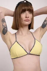 Top de bikini negro con ribete amarillo, corte triangular y tirantes finos.