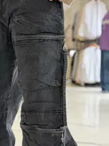 Pantalón cargo de jean negro con efecto acid wash, corte oversize, tiro medio y múltiples bolsillos laterales con solapa y cierres colgantes.