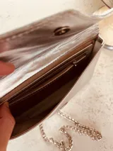 Cartera de fiesta plateada con solapa texturizada y cadena metálica.