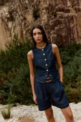 Shorts de denim azul oscuro, tiro alto, con pinzas delanteras y corte ancho. Incluye un cinturón fino marrón con hebilla de eslabones dorados.