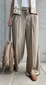 Pantalón palazo de lino color tostado, de calce amplio y fluido, con tablas en el frente y cordón ajustable en la cintura.