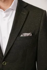 Blazer de corte slim fit en color marrón con textura jaspeada, cierre frontal de dos botones, solapas clásicas y bolsillo en el pecho con pañuelo decorativo.