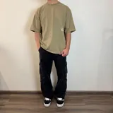 Remera negra de corte oversize con estampado gráfico en la espalda que presenta hongos en tonos violeta y verde, junto con la frase 'Curbside Treasures' y texto descriptivo.