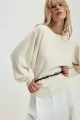 Jersey de punto negro con cuello barco y mangas largas amplias. Presenta un diseño ajustado en la cintura con un cinturón fino integrado que incluye una hebilla metálica dorada.