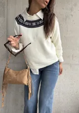 Sweater de punto color natural con cuello redondo y detalle de guarda tejida en la parte superior del pecho. Presenta mangas largas con puños acanalados y un diseño de corte recto.