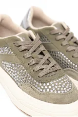 Championes urbanos de cuero legítimo y gamuza color verde oliva, decorados con tachas plateadas en los laterales y la puntera. Poseen suela chunky de goma blanca y cordones al tono.