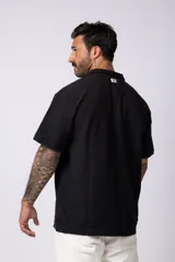 Chomba de manga corta con cuello polo, confeccionada en tejido de punto acanalado de textura pesada. Presenta un calce relajado y cuenta con una pequeña etiqueta distintiva en el ruedo.