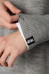 Sweater oversize de tejido de algodón color beige, con cuello redondo, puños y ruedo acanalados con detalles de desgaste. Presenta un diseño minimalista con etiqueta distintiva en el puño.