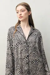 Camisa de pijama de silueta relajada, con estampado orgánico en tonos beige y negro. Cuenta con cuello camisero, cartera frontal con botones negros y vivos en contraste.