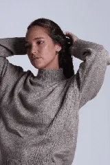 Sweater color beige de tejido de punto con cuello alto y mangas largas. Presenta detalles de ochos en diagonal en los laterales.