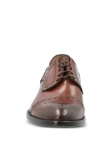 Zapato de vestir tipo Oxford con diseño brogue, confeccionado en cuero vacuno de color marrón. Presenta cierre mediante cordones, puntera redondeada con detalle de perforaciones decorativas y suela mixta de cuero y goma.
