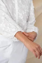 Camisa/chaqueta blanca de algodón con bordado floral en hilo de seda al tono, manga ancha terminada en frunce y botones forrados.