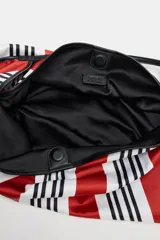 Maxi bolsa tipo shopper con diseño estampado de rayas en color rojo, blanco y negro, asa de hombro y cierre con botón imantado.