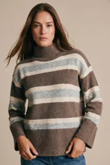 Polera de tejido de punto con diseño a rayas horizontales en tonos marrón, beige y gris. Presenta cuello alto, mangas largas con puños anchos y un corte holgado.