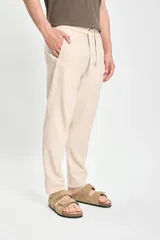 Pantalón casual color beige confeccionado con lino y elastano, de corte recto y largo hasta el tobillo.