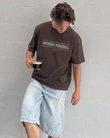 Remera marrón oversize de manga corta con estampado gráfico en la espalda de dos gatos de estilo retro con cuchillos y texto "Kahoa Industries".