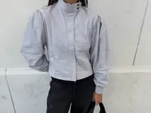 Campera entallada de bengalina color celeste, con cierre frontal, cuello subido, bolsillos delanteros y mangas acampanadas con botones a presión en los puños.