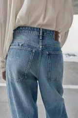 Jeans de tiro alto, color celeste claro con efecto desgastado y lavado. Modelo de corte holgado (loose baggy) con cierre frontal de botones metálicos y cinco bolsillos.