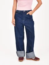 Jean de mujer color azul oscuro, de corte recto y tiro alto, con costuras verticales decorativas en la parte delantera de las piernas. Presenta dobladillo ancho en los tobillos.