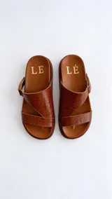 Sandalias de cuero color marrón con textura efecto cocodrilo, plantilla anatómica y diseño de tiras cruzadas asimétricas.