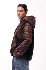 Campera con capucha, cuerpo de pelo sintético y mangas matelaseadas con cierre frontal.