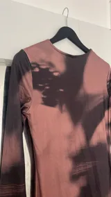 Vestido midi marrón con estampado abstracto en negro, de corte ajustado y manga larga.