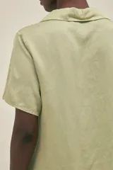 Camisa verde pistacho de manga corta con cuello camisero y botones anacarados, confeccionada en tejido lino-tencel.