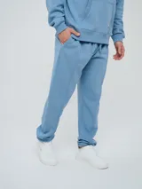 Pantalón jogger celeste de felpa, con cintura elástica ajustable con cordón, puños elastizados en los tobillos y un parche con el logo de la marca en la pierna izquierda.