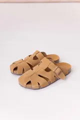 Zuecos de gamuza color tostado, con diseño de tiras entrelazadas, hebilla lateral regulable y suela baja con plantilla anatómica.