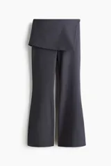 Pantalón acampanado de tiro alto con pollera mini integrada en la cintura, confeccionado en tela lisa de color gris oscuro.