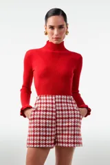 Buzo de punto rojo con cuello alto y mangas largas con volados en los puños.