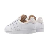 Championes Adidas modelo Superstar, de diseño clásico en color blanco total, con la icónica puntera de goma y las tres bandas laterales perforadas.