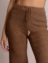 Pantalón de tiro alto con tejido calado y textura labrada, de corte recto con apertura acampanada hacia el ruedo. Cuenta con cintura elastizada y cordón de ajuste con terminaciones de caracoles decorativos.