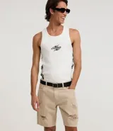 Bermuda masculina de sarga color beige con corte slim, diseño con roturas estilo destroyed y cierre tradicional de botón y cremallera.