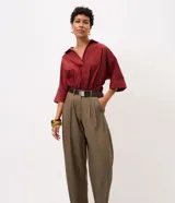 Pantalón de sintonía sastrera corte barrel color verde militar, de diseño estructurado con volumen suave en las piernas y terminación afinada. Cuenta con cintura con pasacintos, pinzas delanteras, bolsillos laterales y cinturón desmontable con hebilla metálica.