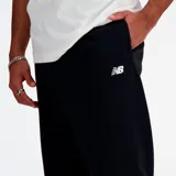 Pantalon de jogging New Balance color negro, con corte holgado y puños elásticos en los tobillos. Presenta el logo de la marca bordado en blanco en la parte superior de la pierna izquierda.
