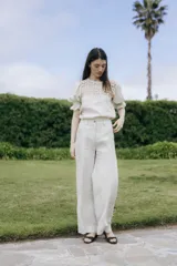 Pantalón de lino de pierna amplia y corte recto, color beige, con trabillas para cinto y cierre frontal con botón.